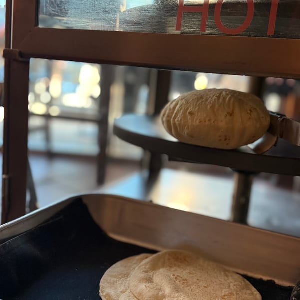 Freshly baked tortillas in a warmer with a "CAUTION HOT" sign visible.