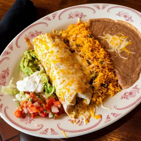 A cheesy burrito with rice, refried beans, guacamole, pico de gallo, and sour cream.