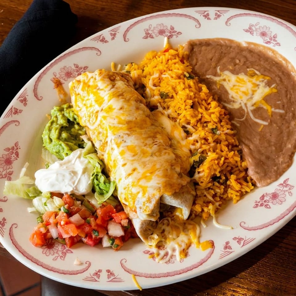 A cheesy burrito with rice, refried beans, guacamole, pico de gallo, and sour cream.