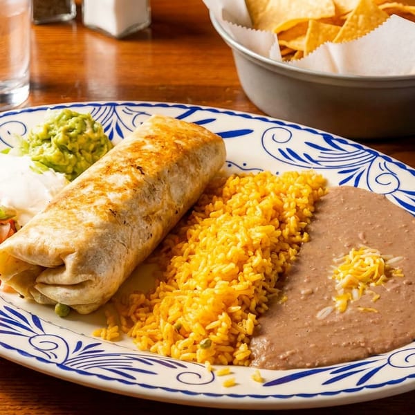A large burrito plate with rice, refried beans, guacamole, sour cream, and pico de gallo.